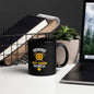 11 oz black glossy Bitcoin-themed coffee mug with “Mining My Own Business” design, placed on white desk beside books and laptop.